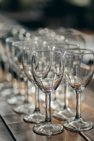 A close-up view of multiple empty wine glasses arranged in rows on a wooden table.の写真素材