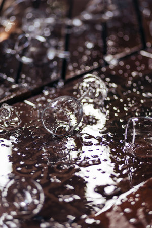 Close up of broken wine glasses and spilled wine, parts of the broken glass on floor with water splash on wooden terraceの写真素材