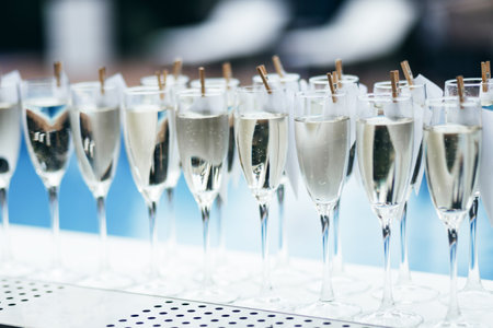Glasses with cold sparkling wine standing on a counter in a row, swimming pool in back, party barの写真素材