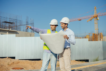 Team of building experts with drawings inspecting new development site