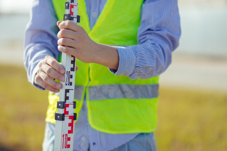 Worker is unfolding leveling rod on construction site.の写真素材