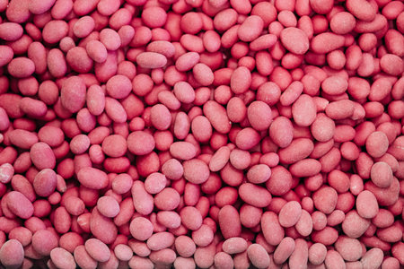 Color pink candies background. Nuts in pink glaze dragee. Sweets texture, pattern. Top view, flat...