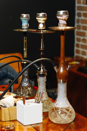 Three hookahs of different flavors stand on a table in a restaurant