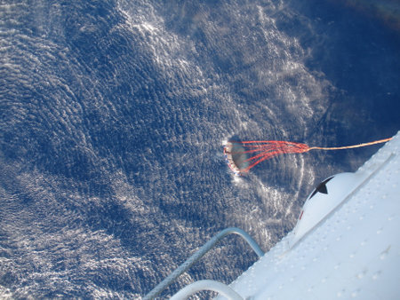 Helicopter collecting water in a bucket from a pond for fire fighting, view from aircraftの写真素材