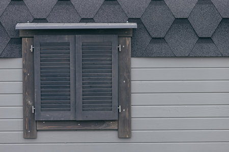Gray wood plank facade with window closed with wooden shuttersの写真素材