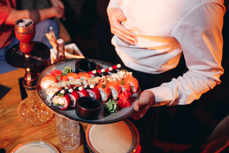 Waiter carries in his hands plate with sushi setの写真素材