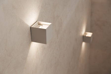 Small wall lamps on the staircase in a private house. Beige color, marble