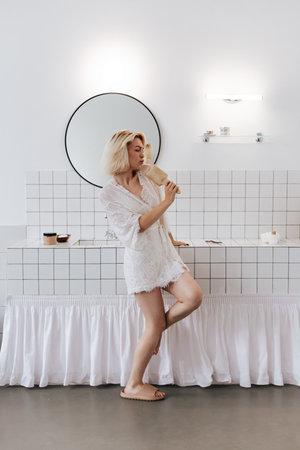 Young woman singing with comb as mic and dancing at home bathroomの写真素材
