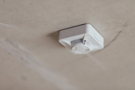 White Smoke Detector Installed On Concrete Ceiling. Fire Safety Device In Unfinished Interior.