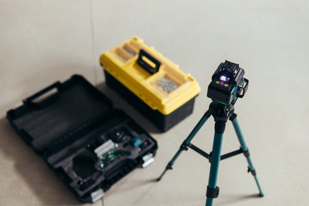 Laser Level Mounted On Tripod Next To Tool Cases. Professional Construction Equipment Arrangement.