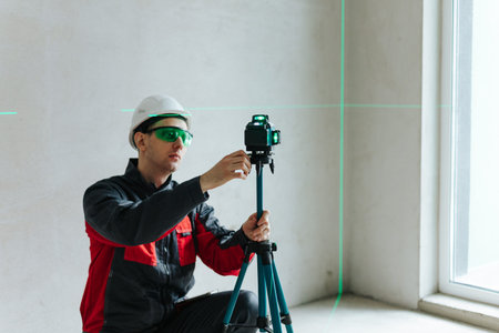 Technician Adjusting Laser Level While Wearing Safety Glasses And Helmet. Precision Alignment In...