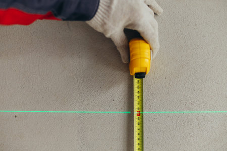 Hand Holding Tape Measure Vertically Along Laser Line On Wall. Height Measurement In Construction...