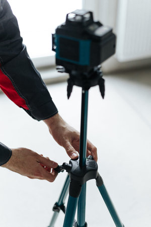 Hands Tightening Tripod Leg Clamp To Set Laser Level Height