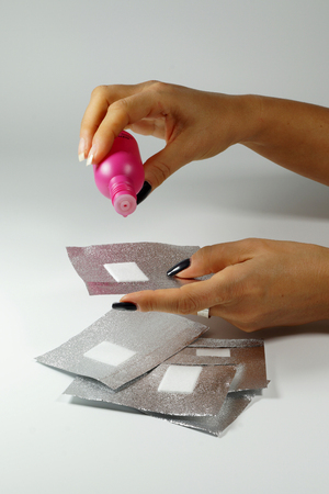 Gel nail polish remover and gel nail polish remover foils for hybrid varnish. Woman dispenses the remover on the foil-verticalの写真素材