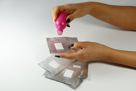 Gel nail polish remover and gel nail polish remover foils for hybrid varnish.Woman dispenses the remover on the foil-horizontal.の写真素材