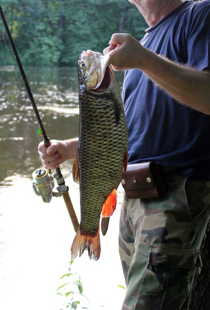 Angler with his prey on the river bankの写真素材
