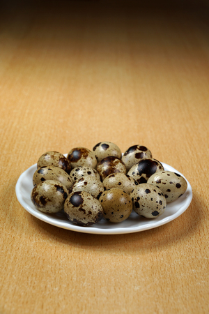 Quail eggs on a wooden table, on a plateの写真素材