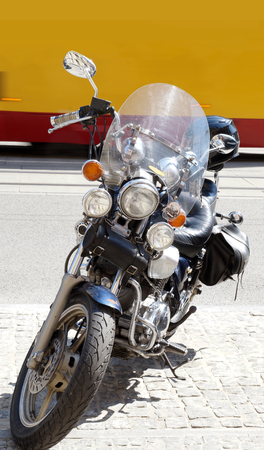 A motorcycle parked on a busy street. Buses and trams travel in the background.の写真素材