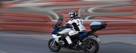 Fast motorcyclist riding on the background, which emphasizes the driving dynamics.の写真素材