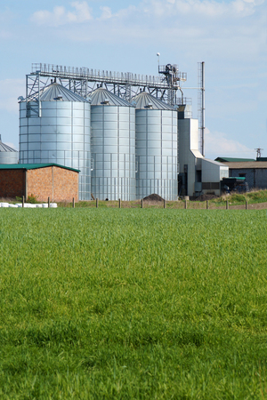 Silos for feed. A feed mixer in a large farm against a background of arable fields. Vertical frame.の写真素材