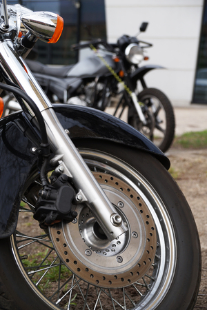 Close-up of the front wheel, brake disc, shock absorbers. In the background an out of focus second motorcycle.の写真素材