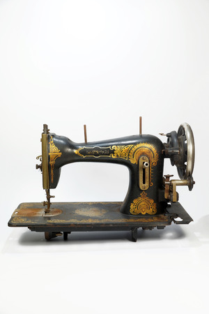 The whole silhouette of an old antique sewing machine, a machine decorated with golden ornaments. Vertical frameの写真素材