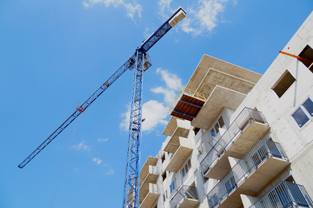 Horizontal frame shot from the construction site, view from below on the building being built and a construction crane.の写真素材