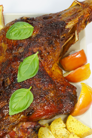 Close-up of baked turkey thigh with apples and potatoes served on a large plate, vertical photo arrangementの写真素材