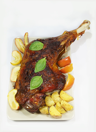 Baked turkey thigh with apples and potatoes served on a large plate, vertical arrangement of the photoの写真素材