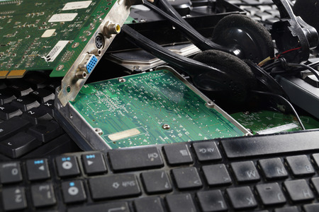 A heap of old computer parts: keyboards, disks, headphones, graphics cards. E-scrapの写真素材
