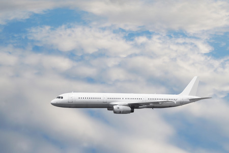 The white passenger plane flies against a slightly cloudy skyの写真素材