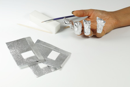 Gel nail polish remover and gel nail polish remover foils for hybrid varnish. A woman's hand with foilsの写真素材
