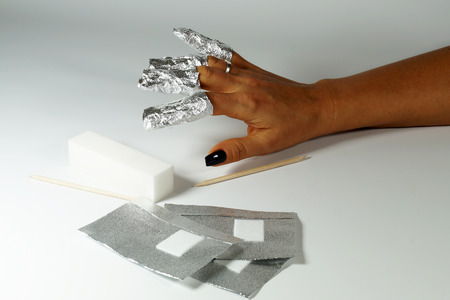 The procedure for removing varnish from nails (hybrid nails) in progress. Gel nail polish remover foils on woman's hand.の写真素材