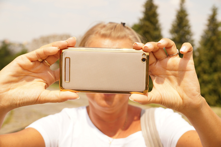 A young woman is taking a picture with a smartphone.の写真素材