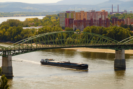 Shipping on the Danube. A barge sailing under the bridge connecting Sturovo in Slovakia and Esztergom in Hungary.の写真素材