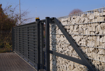 Automatic entrance gate used in combination with a wall made of gabion.の写真素材
