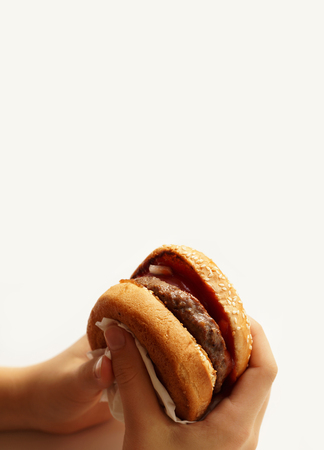 Burger in the hands of a teenager on a white background. A popular meal.の写真素材