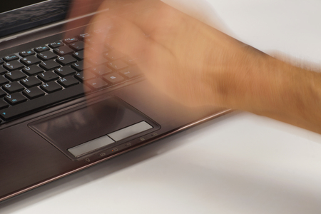 A male hand violently striking a laptop touchpad. The computer does not want to work properly.の写真素材