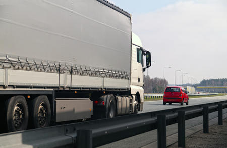Highway. Two different road users: a large truck and a small passenger car.の写真素材