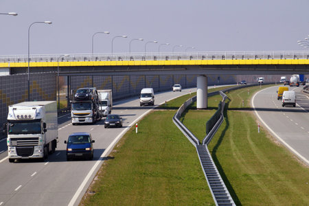 Various cars moving on the highway. In the distance, a view of a road overpass.
