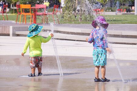 Hot summer. Colorful children dressed in streams of water from the fountain.の写真素材