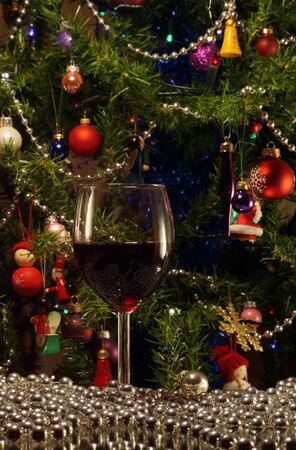 A glass of red wine on the background of the Christmas tree. In a festive mood.の写真素材