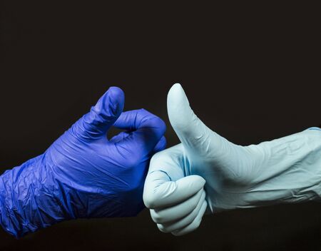 Positive symbol - thumbs up. Two people make this gesture in protective gloves.の写真素材
