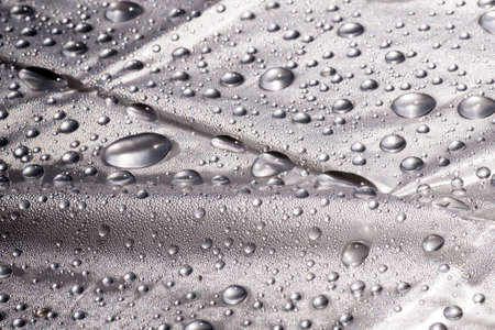 Water drops on the surface covered with foil. Surface tension.の写真素材