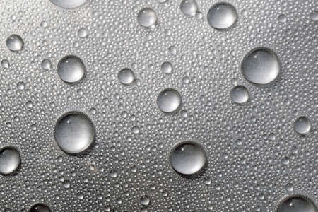Water drops on the surface covered with foil. Surface tension.の写真素材