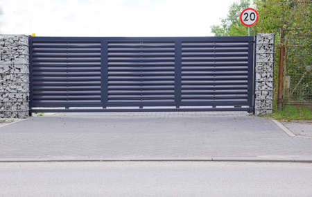 Automatic entrance gate used in combination with a wall made of gabion.の写真素材