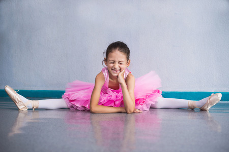 Young ballerina in pink clothes sitting on the floor during the training in dance class.の写真素材