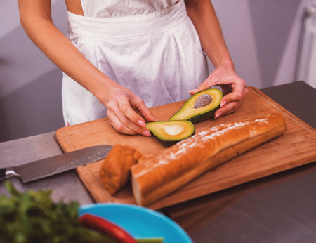 Woman holding fresh avocado in kitchen