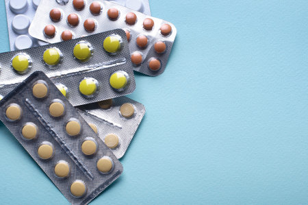 Assorted pharmaceutical medicine pills, tablets and capsules over blue background