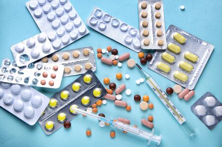 Medicine green and yellow pills or capsules on blue background with copy space. Drug prescription for treatment medication. Pharmaceutical medicament, cure in container for health. Antibiotic closeupの写真素材